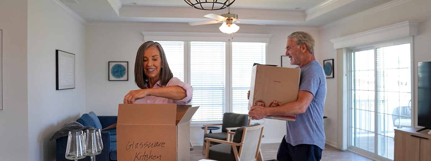 A couple unpacking boxes inside a bright living room