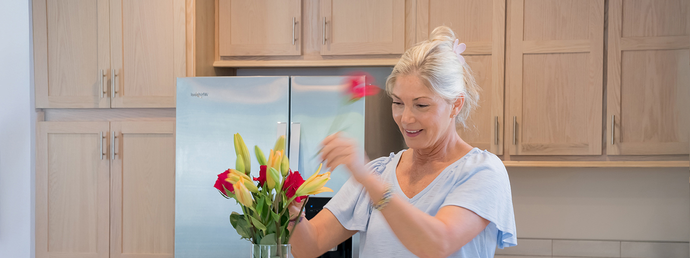 A woman arranging flowers in a kitchen
